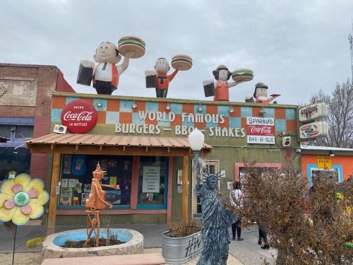 A colorful restaurant facade featuring cartoonish burger characters and a sign for "Sparky's Burgers - BBQ - Shakes."