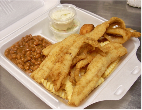 A takeout container with fried fish fillets, crinkle-cut fries, baked beans, and a small cup of dessert.