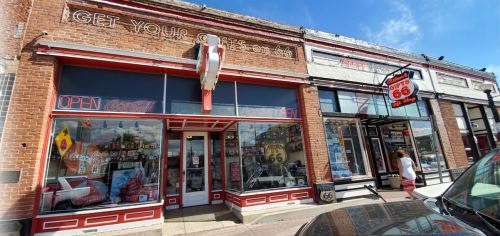 A vintage storefront with "Get Your Kicks on 66" sign, featuring colorful displays and a classic car theme.