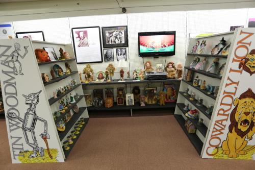 Display of Wizard of Oz memorabilia, featuring shelves with figurines and images of characters like the Cowardly Lion.