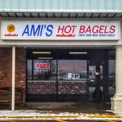 Sign for "Ami's Hot Bagels" with "Open" neon light, showcasing a storefront with a cozy entrance.