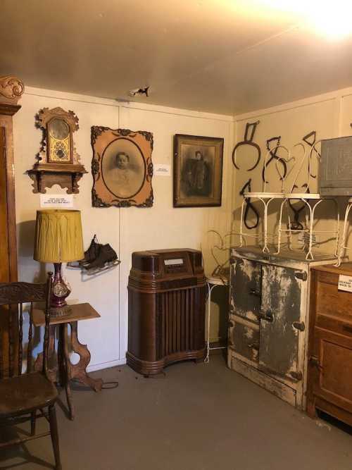 A vintage room displaying various antiques, including portraits, furniture, and old appliances.