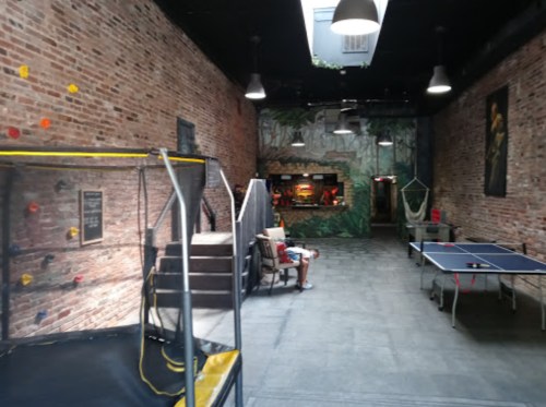 Indoor recreational space featuring a climbing wall, ping pong table, and a bar area with a jungle-themed mural.