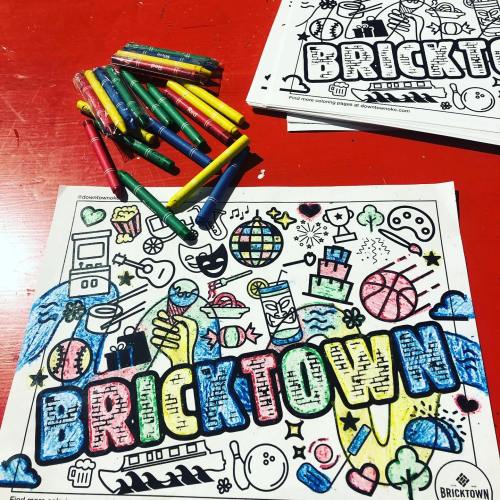 Colorful coloring pages titled "BRICKTOWN" with various doodles, surrounded by markers on a red table.