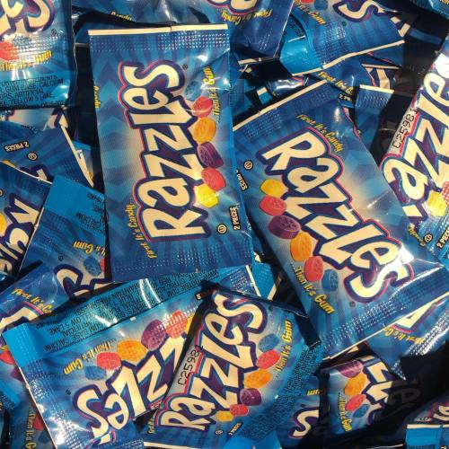 A pile of colorful Razzles candy packages in blue wrappers, showcasing their vibrant colors and playful design.