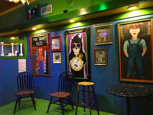Colorful interior featuring artwork, chairs, and a vibrant green floor in a lively setting.