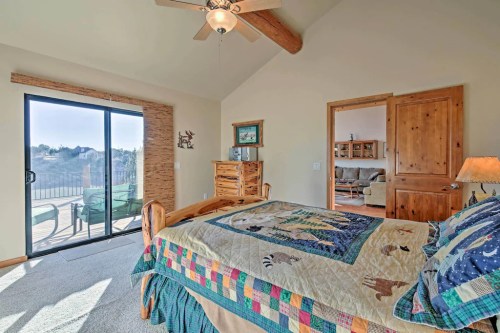 Cozy bedroom with a wooden bed, colorful quilt, and sliding glass door leading to a balcony with scenic views.