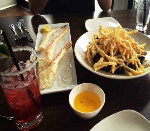 A table setting with a drink, seafood on ice, and a plate of crispy fries.