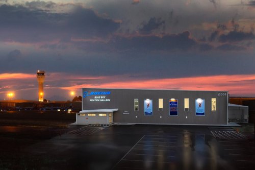 Boeing Blue Sky Aviation Gallery building at sunset, with an airport control tower in the background.