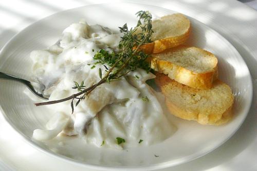 A plate of creamy pasta topped with herbs, accompanied by slices of toasted bread.