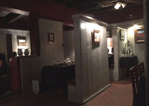Cozy restaurant interior with wooden partitions, dim lighting, and framed artwork on the walls.