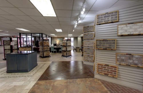 Interior of a showroom displaying various stone and brick samples on walls and a central display table.