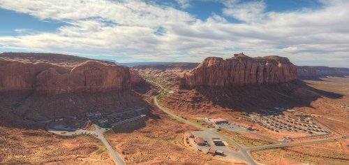 Aerial view of Monument Valley, showcasing red rock formations and a winding road through the desert landscape.