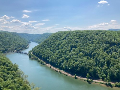 A scenic view of a river winding through lush green hills under a clear blue sky.