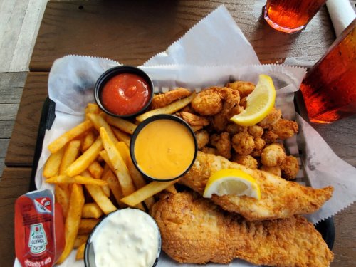 A platter of fried fish, shrimp, and hushpuppies, served with fries and dipping sauces.
