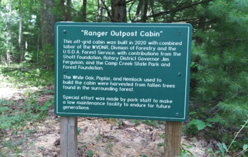 Sign for "Ranger Outpost Cabin," detailing its construction and materials sourced from the surrounding forest.