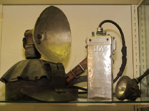 A collection of vintage firefighting equipment, including a helmet, metal canister, and a flashlight.