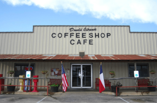 Exterior of Donald Citrano's Coffee Shop Cafe, featuring a metal facade, flags, and an "Open" sign.