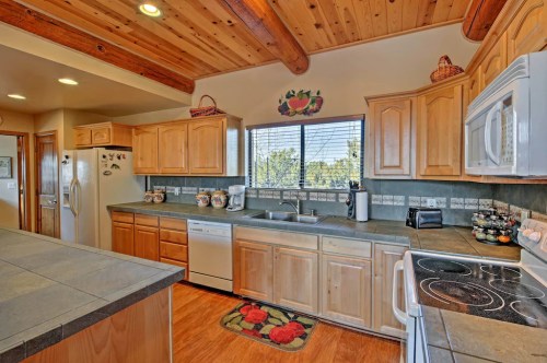 Bright kitchen with wooden cabinets, a large window, and modern appliances, featuring a cozy, rustic design.