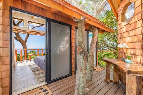 Cozy wooden cabin with a view, featuring a glass door, natural decor, and a serene outdoor space surrounded by trees.