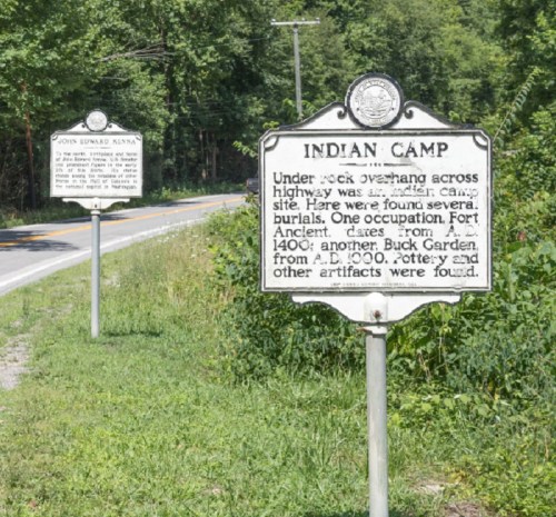Two historical markers along a road, one detailing an Indian camp and the other about John Edward Kunz.