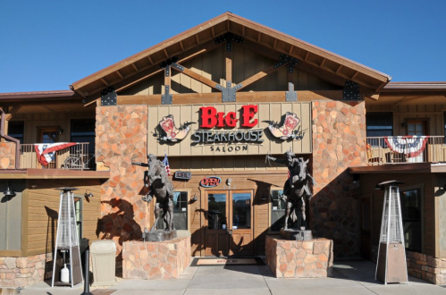 Exterior of Big E Steakhouse Saloon featuring stone walls, wooden accents, and horse statues at the entrance.