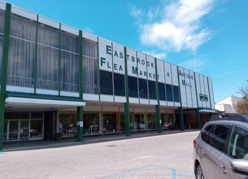 Exterior of Eastbrook Flea Market & Antique Mall, featuring large signage and a clear blue sky.