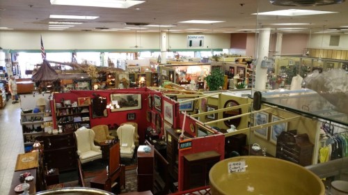 A spacious antique store filled with various furniture, decor items, and displays in a well-lit environment.