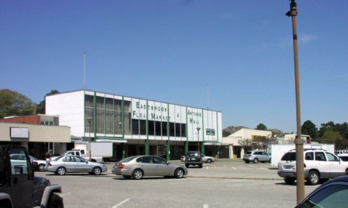 A view of Eastbrook Flea Market and Antique Mall, with parked cars and a clear blue sky in the background.