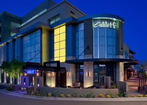 Modern restaurant exterior at dusk, featuring large windows and stylish architecture.