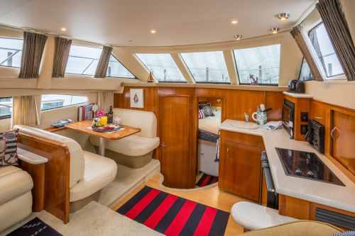 Interior of a yacht featuring a cozy seating area, kitchen, and large windows for natural light.
