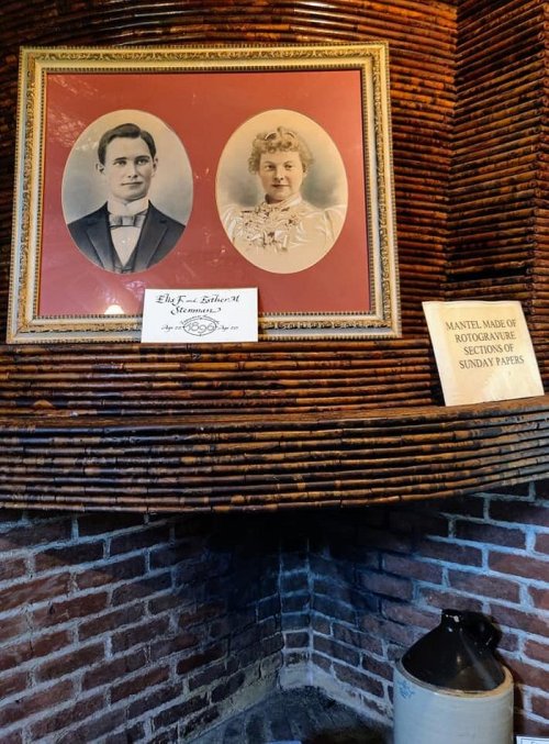 Two vintage portraits of a man and woman framed on a wall, with a plaque below detailing the mantel's history.
