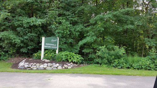 Sign for Hudsonville Nature Center surrounded by lush greenery and landscaping.