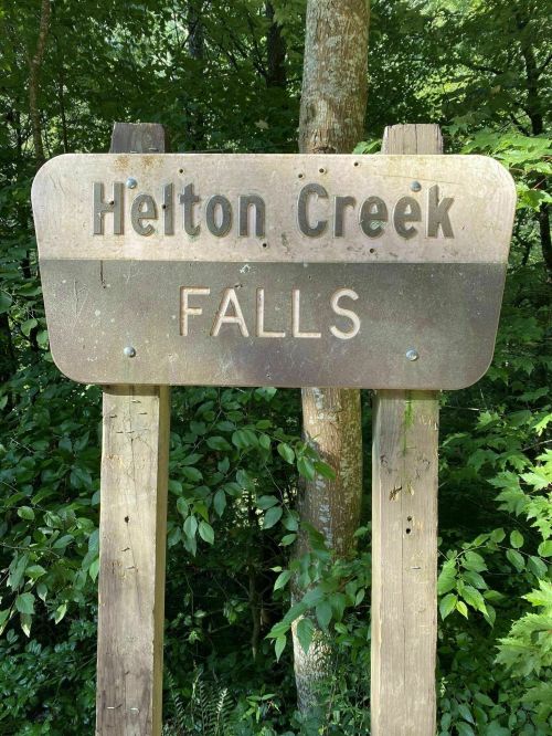 Sign for Heiton Creek Falls surrounded by lush green foliage.