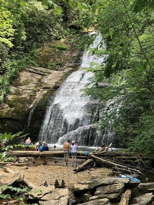 A scenic waterfall surrounded by lush greenery, with people enjoying the water and relaxing on the rocks.
