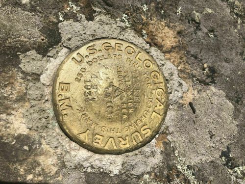 A brass survey marker embedded in a rocky surface, labeled "U.S. Geological Survey" with the year 1934.