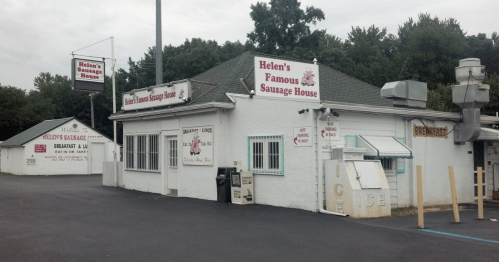Exterior of Helen's Famous Sausage House, featuring signage for breakfast and ice, set in a wooded area.
