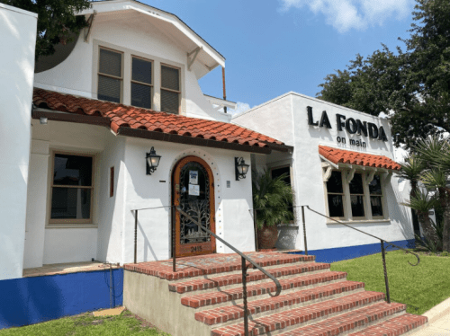 Exterior of La Fonda on Main, featuring a white building with a red tile roof and brick steps.