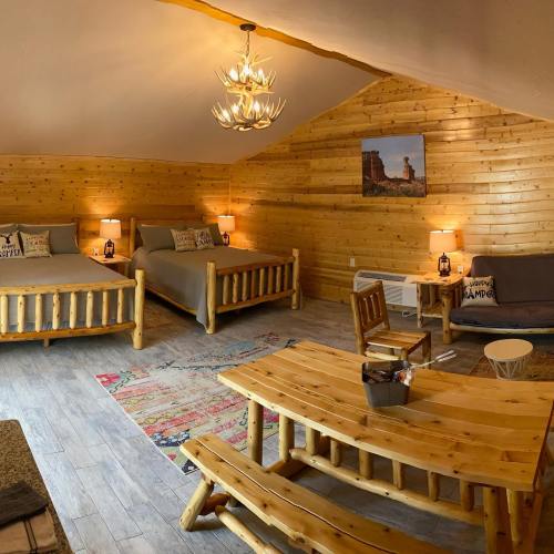 Cozy wooden cabin interior featuring two beds, a dining table, and rustic decor with warm lighting.