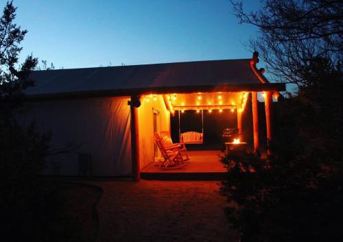 Cozy outdoor space with string lights, a rocking chair, and a fire pit, set against a twilight sky.