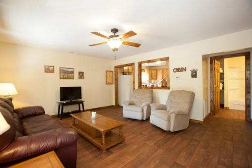 Cozy living room with a TV, two recliners, wooden coffee table, and a view into a kitchen area. Warm, inviting decor.