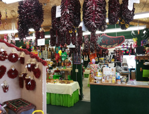 A vibrant store interior filled with colorful decorations, hanging red chilies, and various local products for sale.