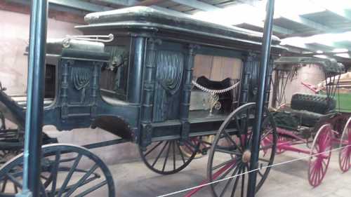 A vintage horse-drawn carriage with ornate details, displayed in a museum setting.