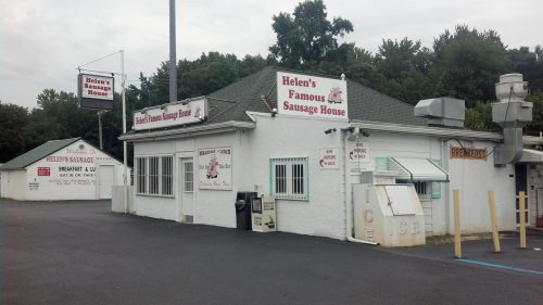 Exterior of Helen's Famous Sausage House, featuring a white building with signage and a parking area.