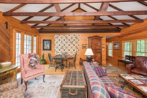 Cozy wooden living room with a dining area, patterned quilt on the wall, and comfortable seating.