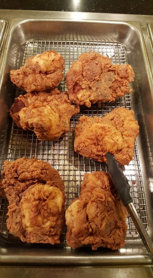 A tray of golden-brown fried chicken pieces resting on a wire rack.