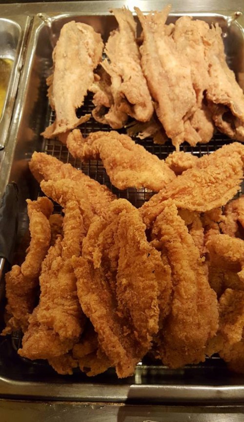 A tray of crispy fried fish fillets, with some pieces stacked on top of each other.