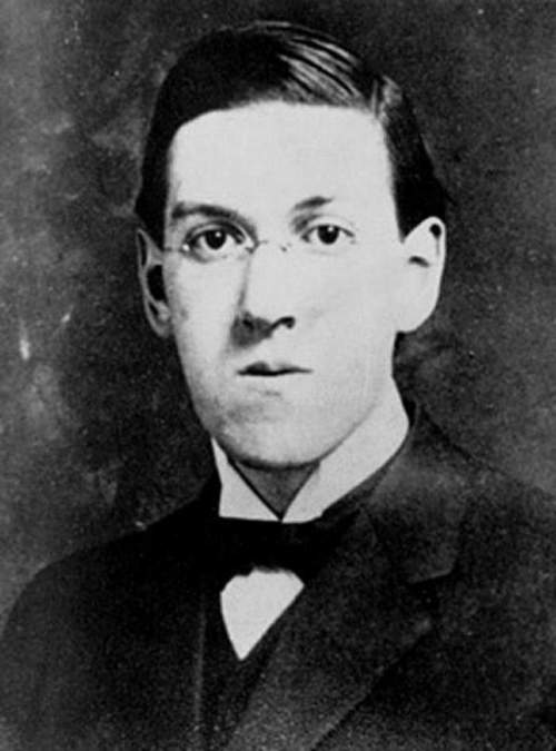 Black and white portrait of a young man with glasses, wearing a suit and bow tie, looking directly at the camera.