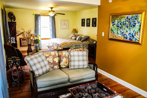Cozy living space featuring a sofa, coffee table, and a bedroom with a bed and decorative artwork on the walls.