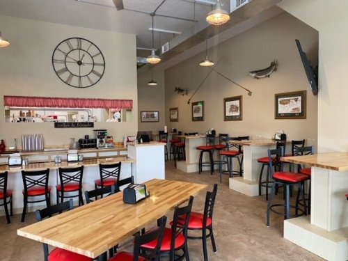 Interior of a casual dining restaurant with wooden tables, red chairs, and a large clock on the wall.